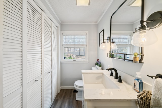 bathroom featuring a closet, a textured ceiling, crown molding, toilet, and a wealth of natural light