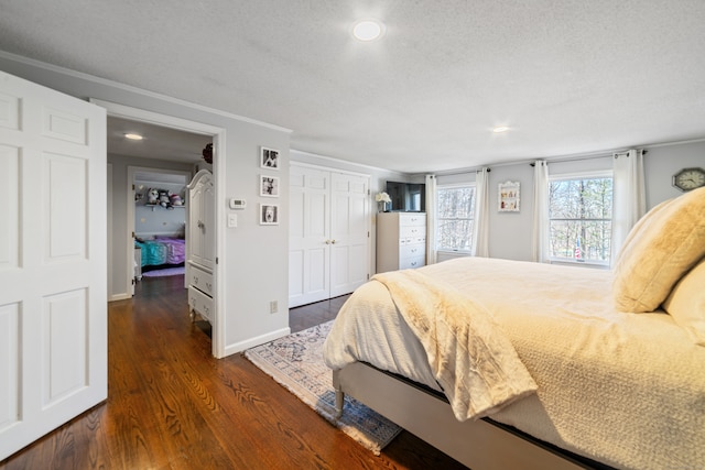 bedroom with a closet, a textured ceiling, baseboards, ornamental molding, and wood finished floors
