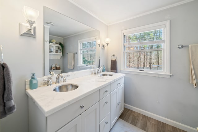 full bath with baseboards, crown molding, wood finished floors, and a sink