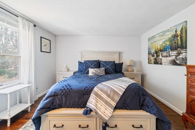 bedroom with baseboards, wood finished floors, and a textured ceiling