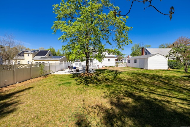view of yard with an outdoor structure, a fenced backyard, and a patio area