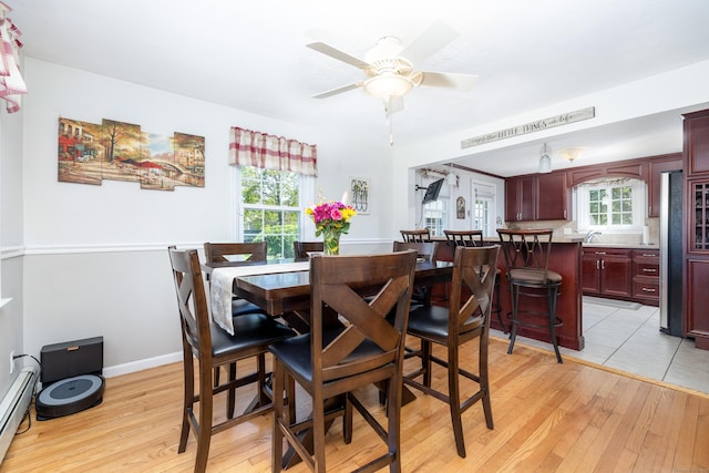 dining room featuring baseboard heating, a wealth of natural light, and light wood-type flooring