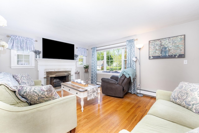 living room with a baseboard radiator, baseboard heating, light wood-type flooring, and a premium fireplace