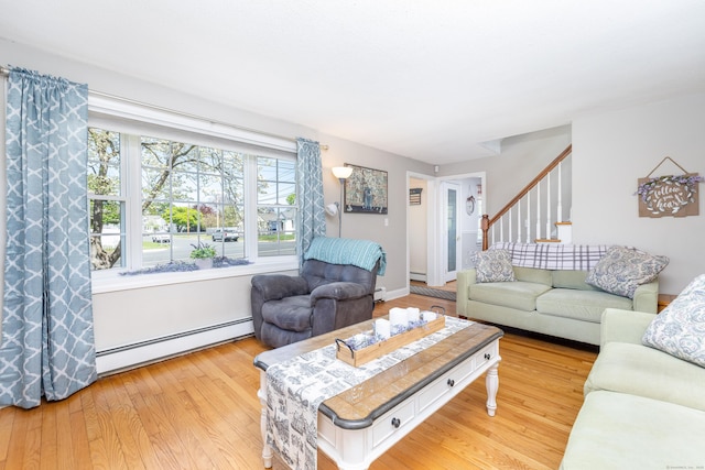 living area featuring stairway, baseboard heating, and light wood-type flooring