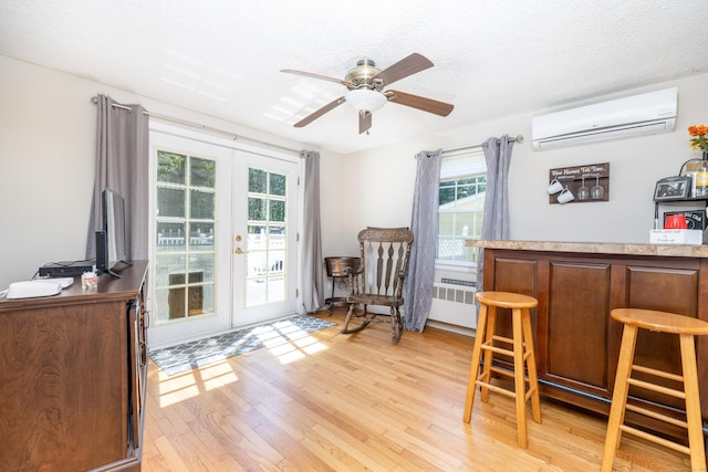 interior space with radiator heating unit, a wealth of natural light, french doors, and a wall mounted air conditioner
