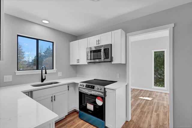 433 Heritage Vlg Unit A, Southbury, CT 06488 - kitchen featuring appliances with stainless steel finishes, a sink, light wood-style floors, light countertops, and white cabinetry