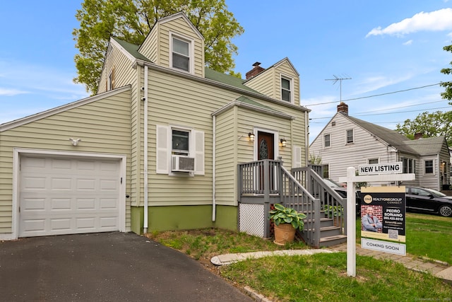 view of front of home featuring a garage, asphalt driveway, cooling unit, and a chimney