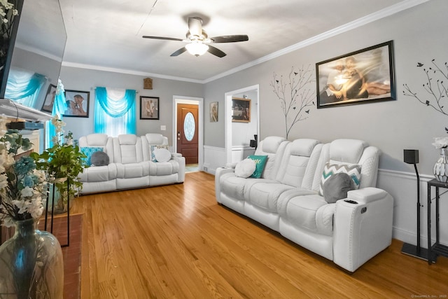 living room featuring ceiling fan, wood finished floors, crown molding, and wainscoting