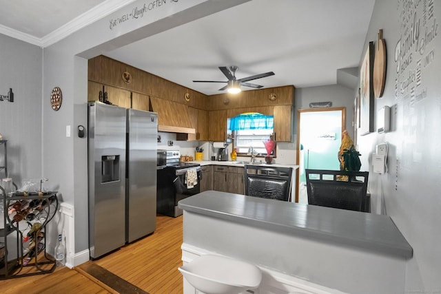 kitchen with stainless steel appliances, light wood finished floors, ceiling fan, ornamental molding, and a peninsula