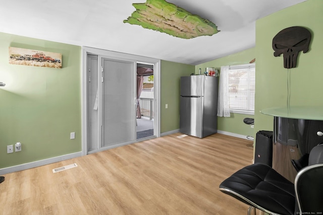 living area featuring vaulted ceiling, light wood-style flooring, baseboards, and healthy amount of natural light