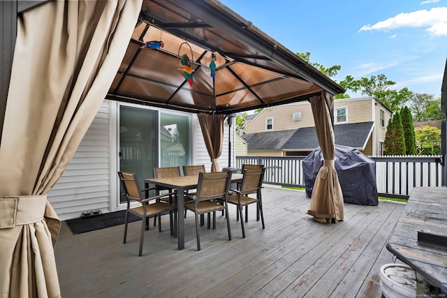 wooden terrace with a gazebo, outdoor dining space, and area for grilling