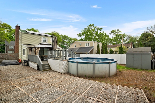 back of property with a gazebo, a storage unit, a wooden deck, an outbuilding, and fence