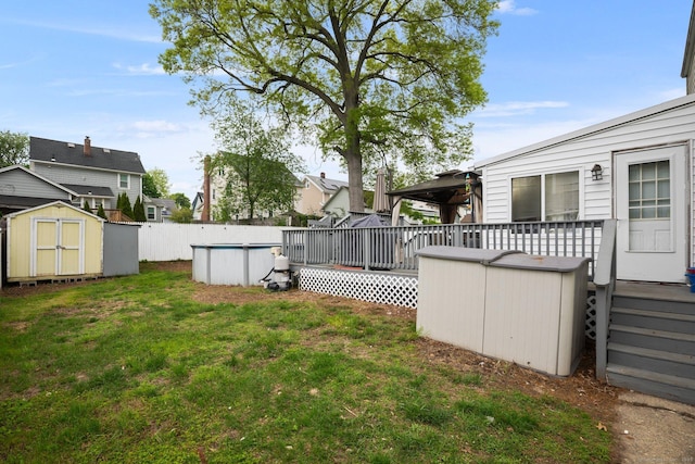 view of grassy yard featuring a storage shed, a wooden deck, and an outdoor structure