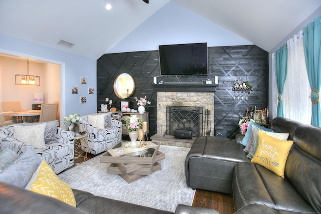 living area featuring a notable chandelier, visible vents, wood finished floors, and a fireplace