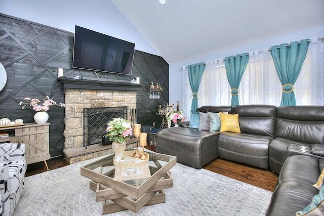 living area with high vaulted ceiling, wood finished floors, and a fireplace