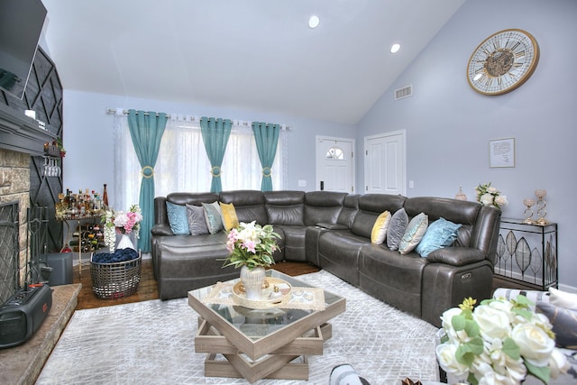 living room with a fireplace, high vaulted ceiling, recessed lighting, wood finished floors, and visible vents
