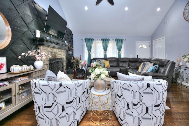 living area with visible vents, wood finished floors, a fireplace, high vaulted ceiling, and a ceiling fan