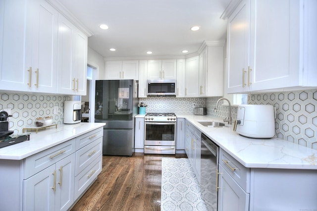 kitchen featuring backsplash, dark wood-style flooring, appliances with stainless steel finishes, a sink, and white cabinetry