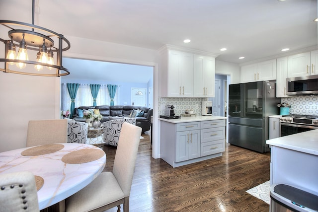 kitchen with a chandelier, appliances with stainless steel finishes, white cabinetry, and dark wood finished floors