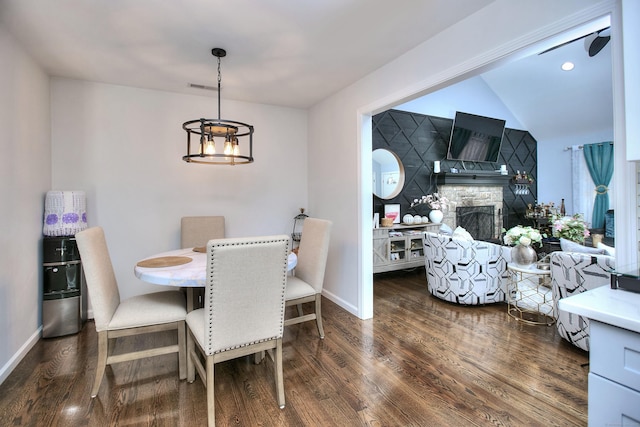 dining room with baseboards, a stone fireplace, wood finished floors, and visible vents