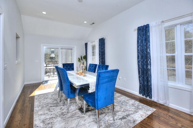 dining space with wood finished floors, baseboards, lofted ceiling, and visible vents