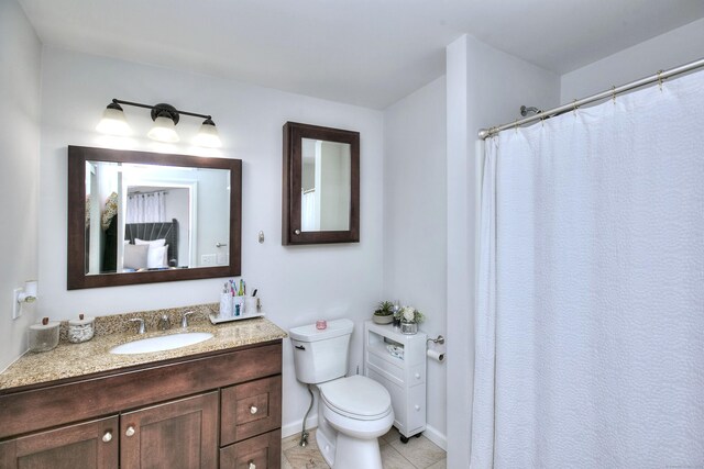 bathroom with vanity, tile patterned floors, baseboards, and toilet
