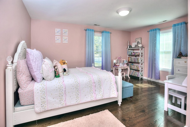bedroom featuring baseboards, wood finished floors, and visible vents