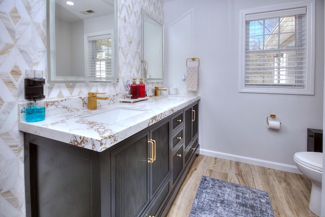 bathroom featuring a sink, visible vents, toilet, and a wealth of natural light