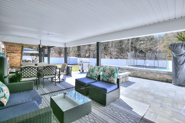 view of patio featuring a trampoline, a fenced backyard, outdoor lounge area, outdoor dining space, and a grill