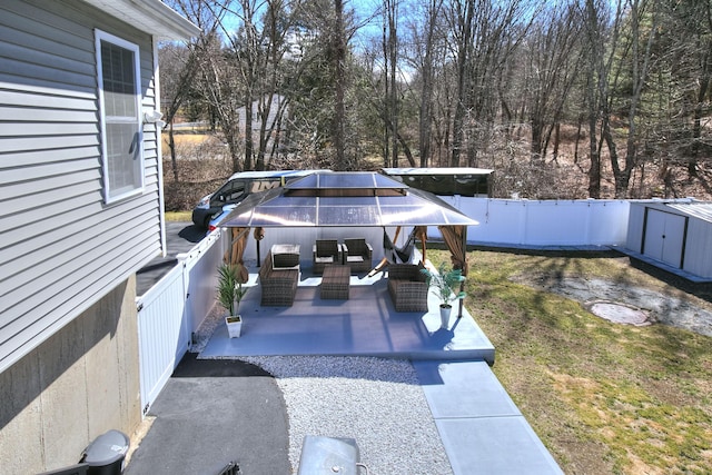 view of patio / terrace with an outdoor living space, a gazebo, an outdoor structure, a fenced backyard, and a storage unit