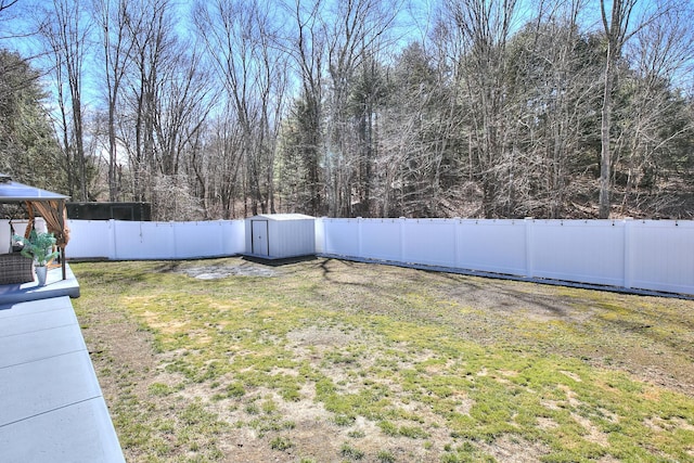 view of yard with a storage shed, a gazebo, an outbuilding, and a fenced backyard