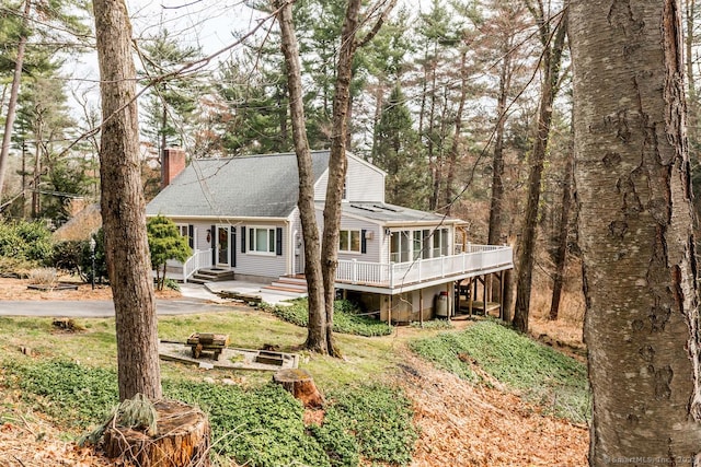 view of front of house with entry steps, a deck, and a chimney