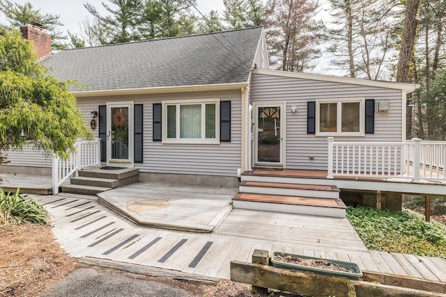 view of front of property featuring a chimney, a shingled roof, and a deck