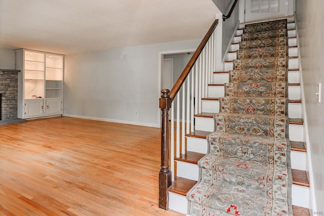 stairway with wood finished floors and baseboards