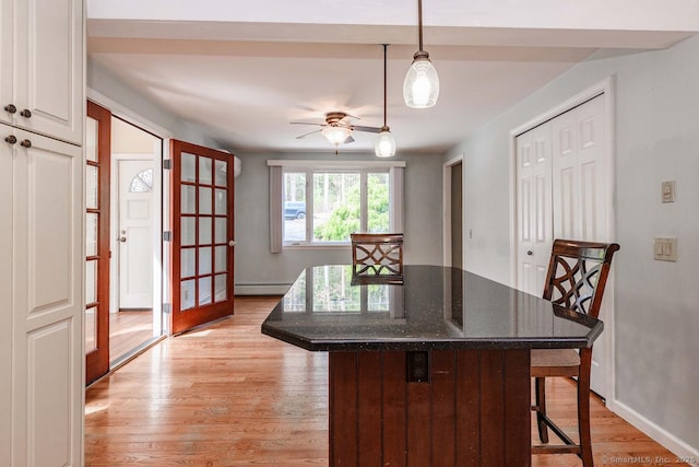 dining area featuring baseboards, light wood finished floors, a baseboard radiator, and a ceiling fan