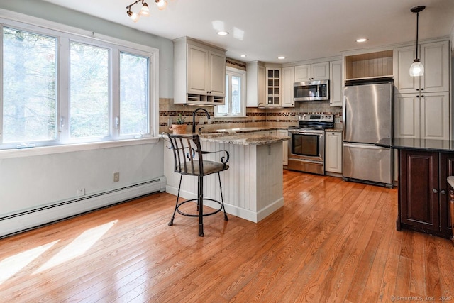 kitchen featuring tasteful backsplash, a sink, light wood-type flooring, appliances with stainless steel finishes, and a peninsula