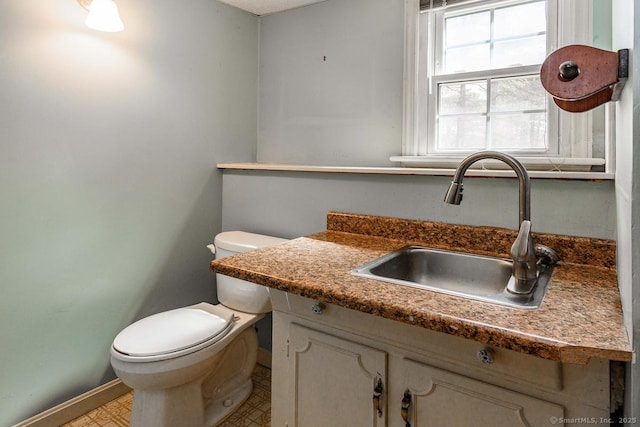 bathroom featuring toilet, vanity, and baseboards