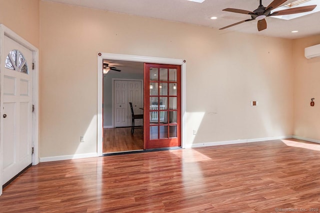 empty room with ceiling fan, baseboards, wood finished floors, and a skylight