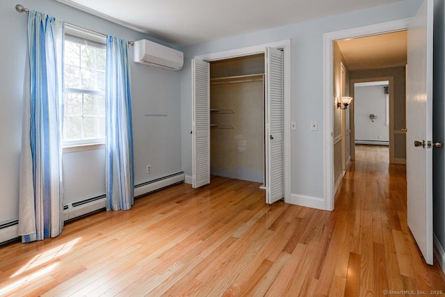 unfurnished bedroom with a baseboard heating unit, light wood finished floors, an AC wall unit, and baseboards