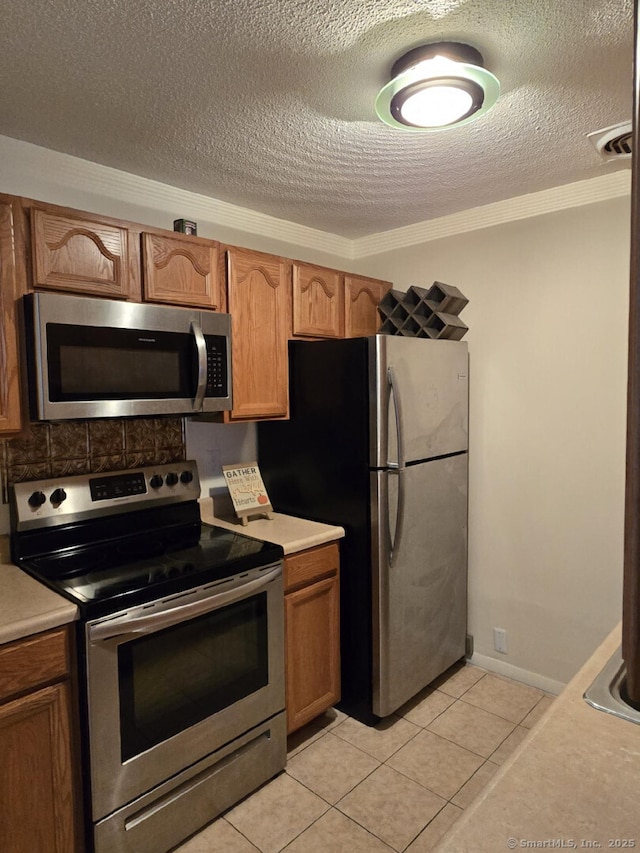 kitchen with a textured ceiling, brown cabinets, stainless steel appliances, and light countertops
