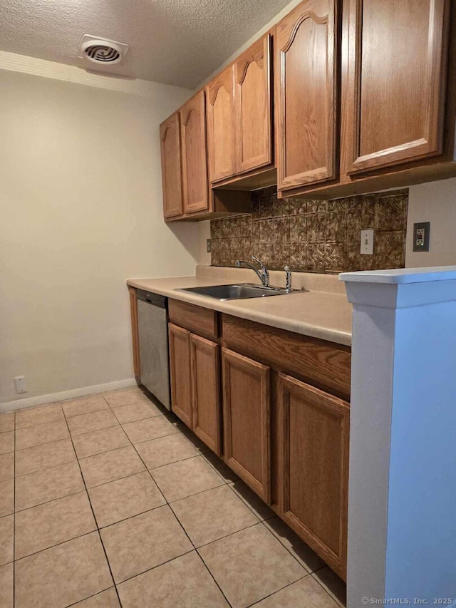 kitchen with a sink, a textured ceiling, dishwasher, and light tile patterned floors