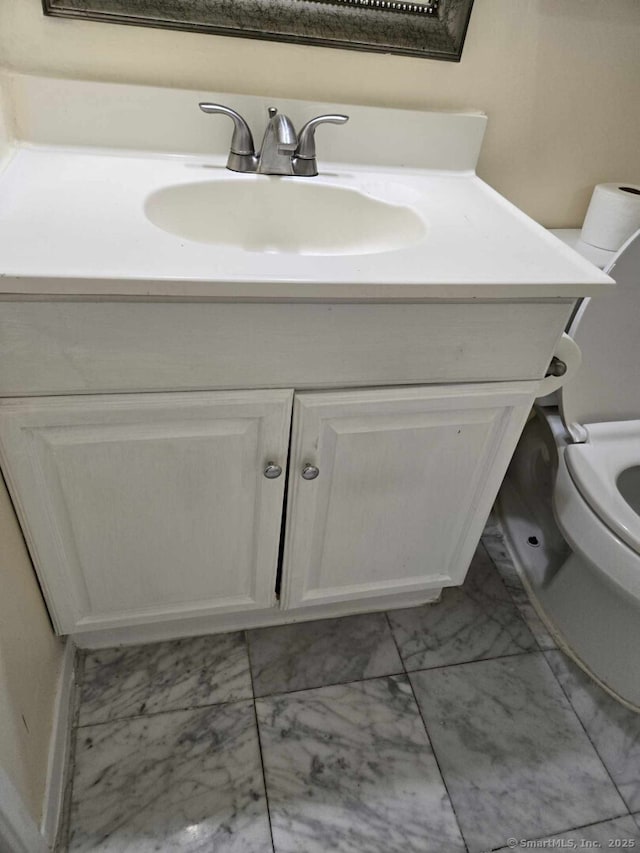 bathroom featuring toilet, marble finish floor, and vanity