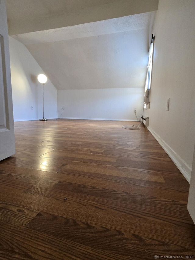 additional living space with lofted ceiling, dark wood finished floors, and baseboards