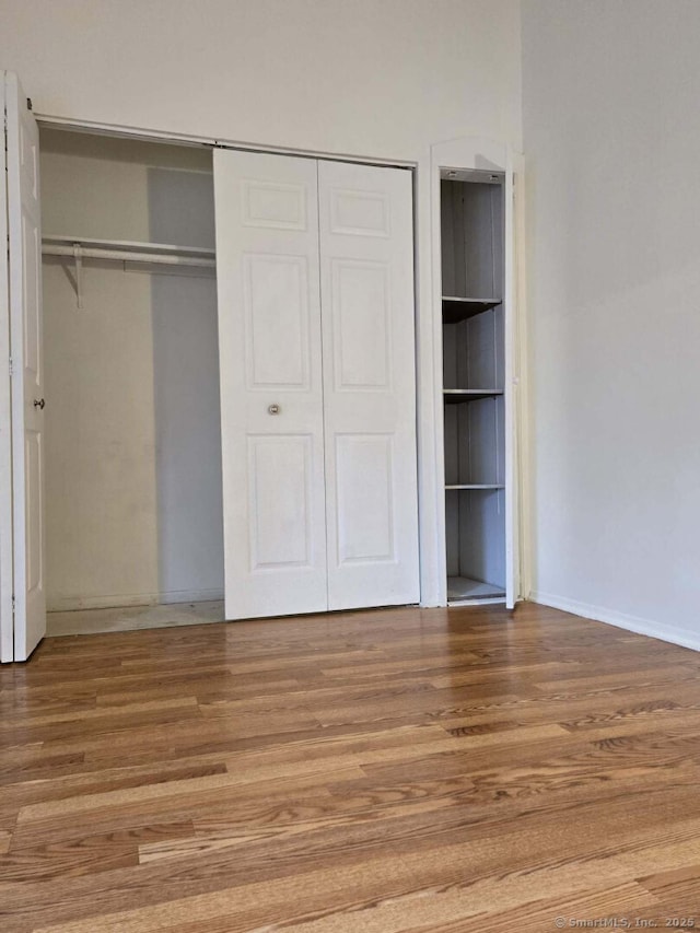 unfurnished bedroom with wood finished floors and a closet