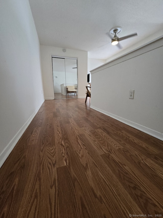 interior space with ceiling fan, dark wood-style floors, and baseboards
