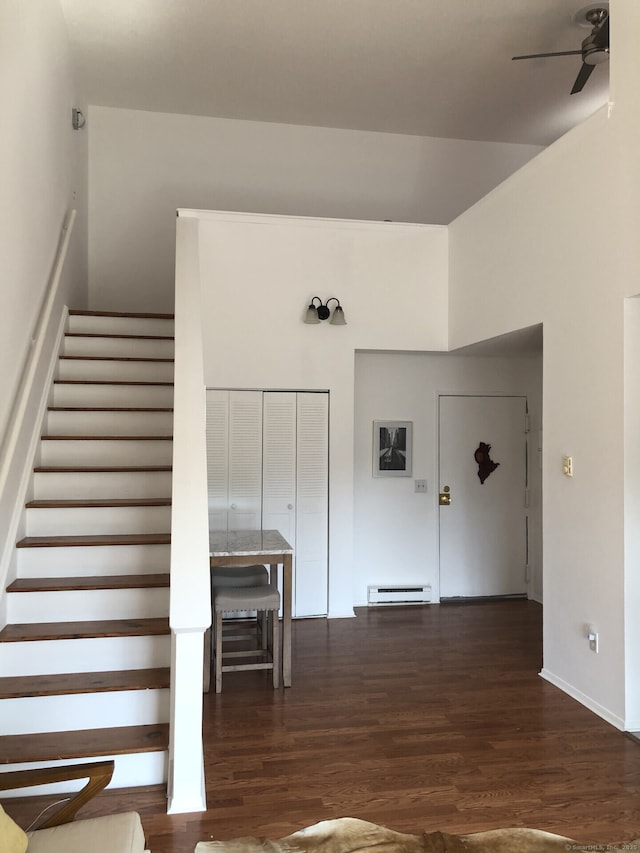 staircase featuring a ceiling fan, wood finished floors, and a baseboard heating unit
