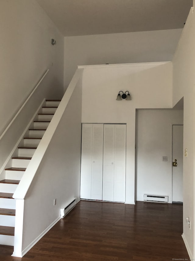staircase featuring wood finished floors and baseboard heating