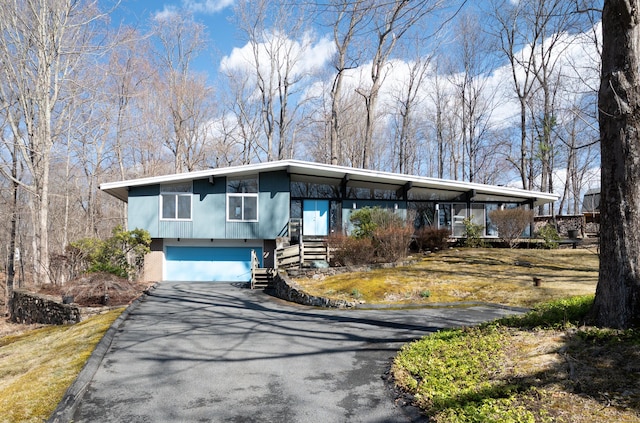mid-century inspired home featuring a garage and aphalt driveway