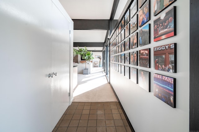 corridor with tile patterned floors, carpet floors, and beam ceiling