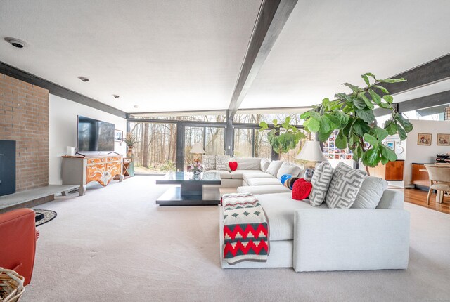 carpeted living room with a fireplace and beam ceiling